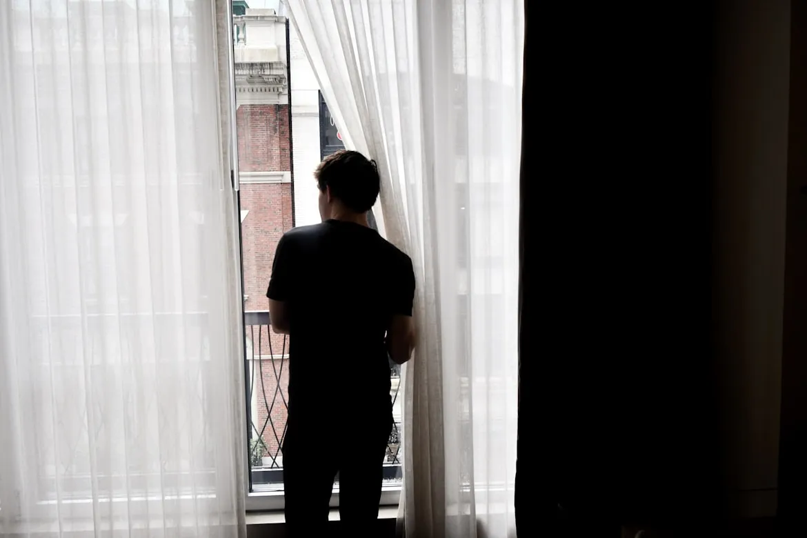 man looking out window afraid of missing out